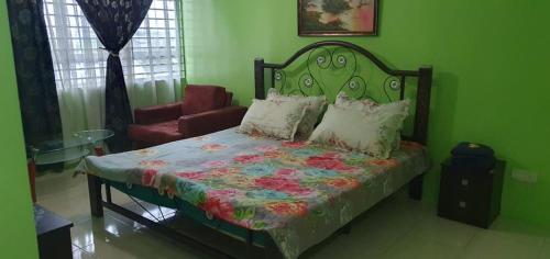 a green bedroom with a bed and a chair at Homestay Shah Alam in Shah Alam