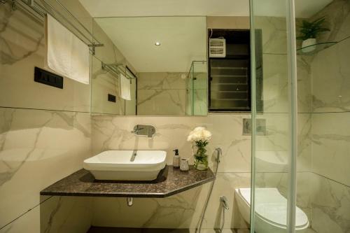 a white bathroom with a sink and a mirror at G S Stay, 2BHK Luxury apartment Baga, Arpora, Goa in Arpora