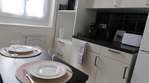 une cuisine avec une table avec des assiettes et des verres dessus dans l'établissement Modern and cozy studio 2 minutes from Porte d'Orléans, à Paris