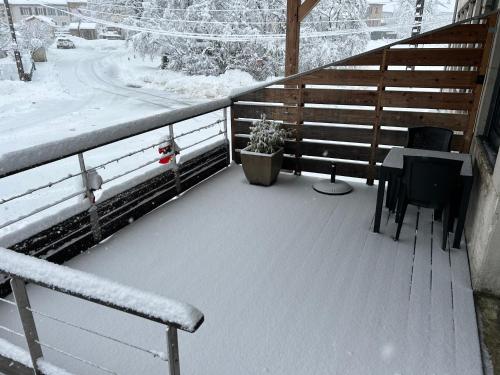 d'un balcon recouvert de neige avec une table et des chaises. dans l'établissement Gîte Cinquetral, à Saint-Claude