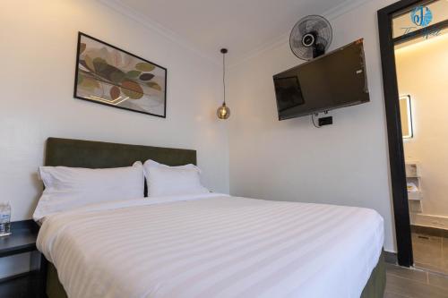 a bedroom with a white bed and a flat screen tv at The Well Kamakis in Nairobi
