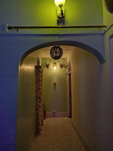 a hallway with a green wall and an archway at Rupali Tat Ghar and Homestay in Majuli