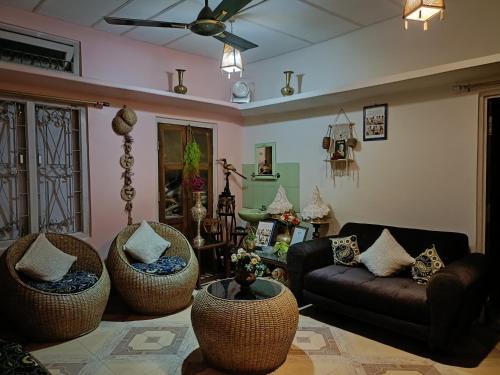 a living room with wicker chairs and a couch at Rupali Tat Ghar and Homestay in Majuli
