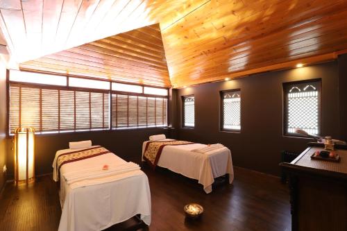 two beds in a room with wooden ceilings and windows at The Chumbi Mountain Retreat & Spa, A Club Mahindra Associate in Pelling