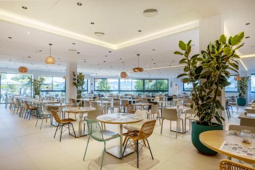 a restaurant with tables and chairs and windows at Els Pins Resort & Spa - Emar Hotels in San Antonio Bay