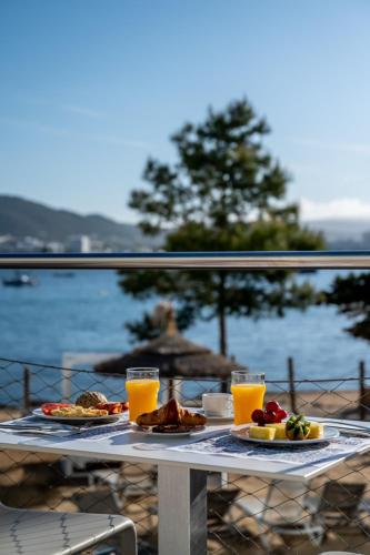 a table with food and two glasses of orange juice at Els Pins Resort & Spa - Emar Hotels in San Antonio Bay