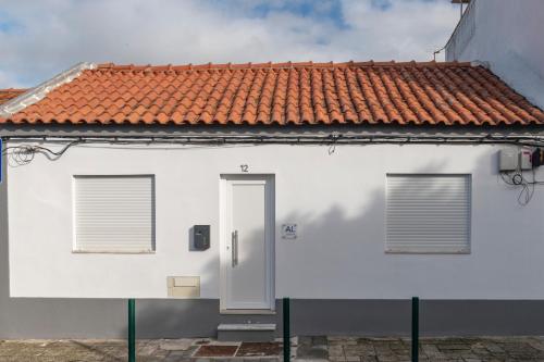 a white house with a red tile roof at Casa do Pátio do Tejo N12 in Sarilhos Pequenos
