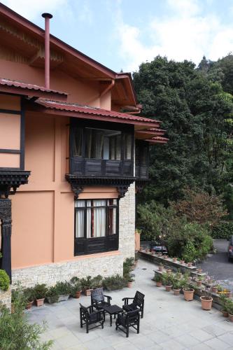 a patio outside of a building with black chairs at The Chumbi Mountain Retreat & Spa, A Club Mahindra Associate in Pelling