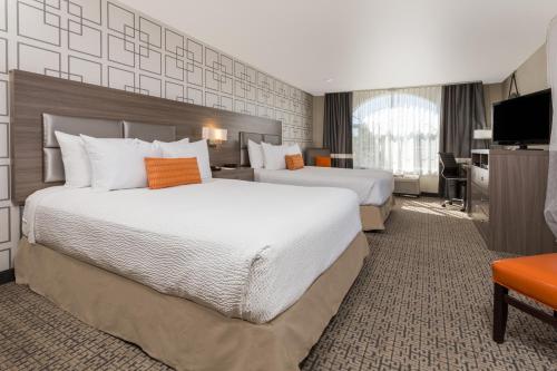 a hotel room with two beds and a desk at Hawthorn Suites by Wyndham Livermore in Livermore