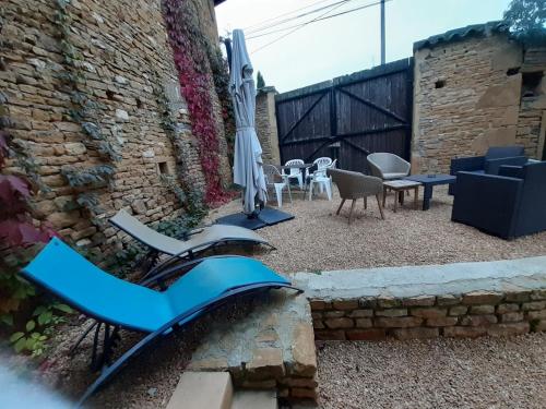 a patio with a table and an umbrella and chairs at Gite dans maison médiévale Calme Fibre 2 ch in Jarnioux