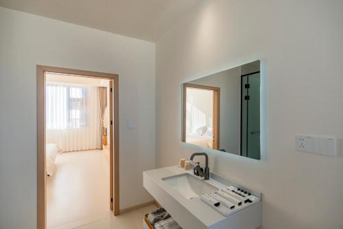 a white bathroom with a sink and a mirror at Yunyuan Private Hot Spring Bed and Breakfast in Sanying
