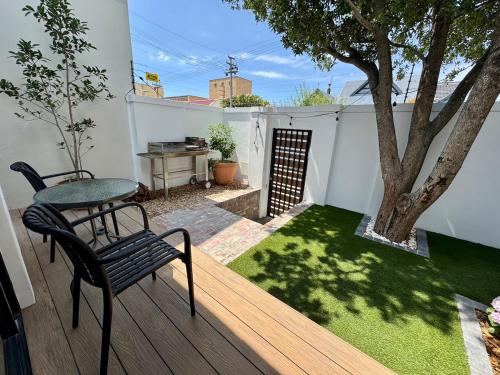 a deck with a table and a chair and a tree at Casa Montanari in Cape Town