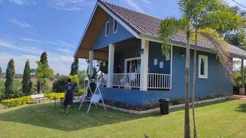 a man standing in front of a blue house at บ้านไร่โฮมเทล ณ ปากช่อง in Ban Nong Takhain