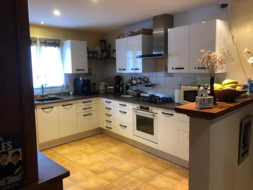 une cuisine avec des armoires blanches et des bananes sur le comptoir dans l'établissement La Cocadière, au Château-dʼOléron