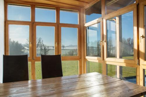 a dining room with a wooden table and windows at Pur Wohnen - Wohnung West in Bad Griesbach