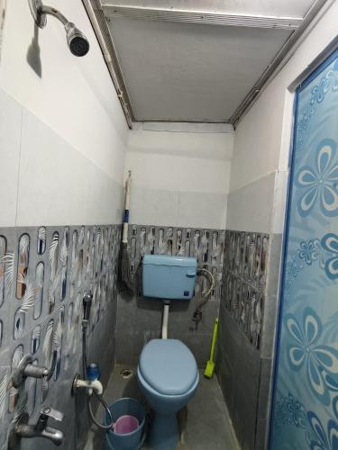 a bathroom with a blue toilet in a room at Rupali Tat Ghar and Homestay in Majuli
