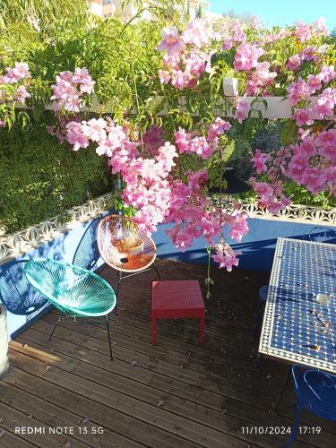 una terraza con mesas, sillas y flores rosas en Studio indépendant terrasse entre mer et collines, en Marsella