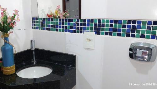 a bathroom with a sink and a vase with flowers at Temporada Belas Casas in São Pedro