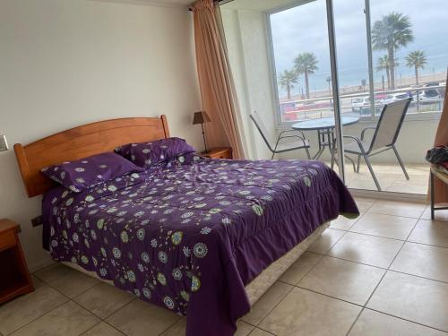 a bedroom with a bed and a balcony with a table at First line, ocean view in Coquimbo