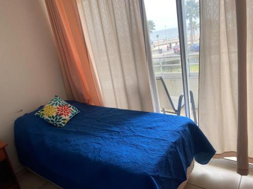 a bedroom with a blue bed with a window at First line, ocean view in Coquimbo