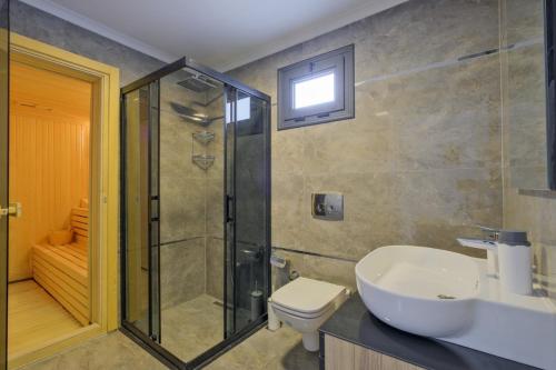 Un baño con ducha, lavabo e inodoro. en Villa White Palm 1, en Fethiye