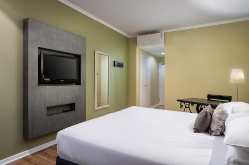 a bedroom with a white bed and a flat screen tv at Protea Hotel by Marriott Bloemfontein in Bloemfontein