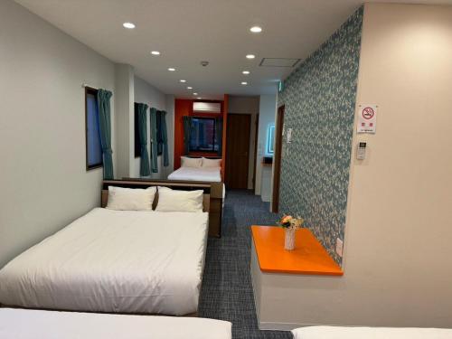 a hotel room with two beds and a table at Guest House新今宫 in Osaka