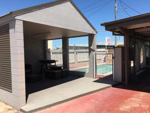 a building with a patio with a table in it at Plantation Park Motor Inn in Ayr