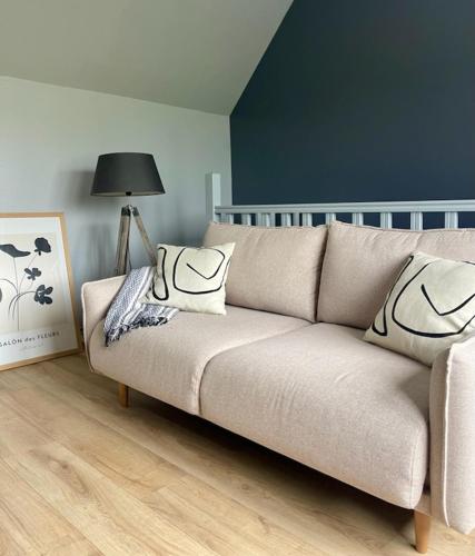 un canapé avec des coussins dessus dans un salon dans l'établissement Naturaë Amentes T2 55M à l' étage, à Saint-Amand-les-Eaux