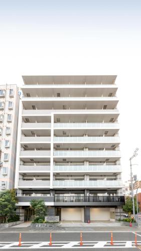 a large white apartment building with a parking lot at 楽宿ー花園北 in Osaka