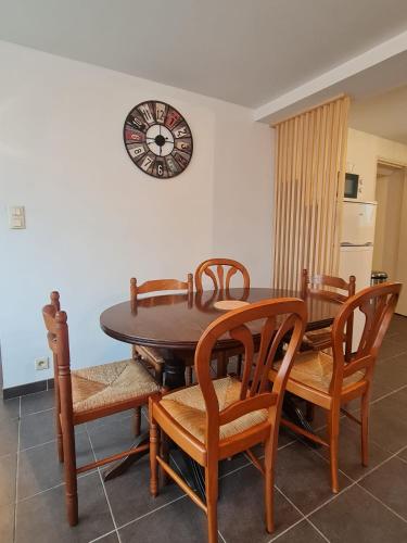 une table à manger et des chaises avec une horloge sur le mur dans l'établissement Appartement familial tout équipé, à Angers