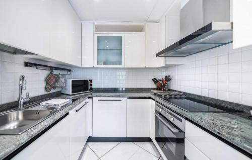 une cuisine blanche avec un évier et un micro-ondes dans l'établissement 2 Bedroom Cozy Apartment In Cannes, à Cannes