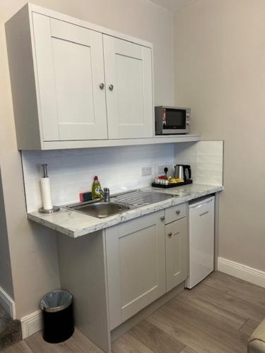 a white kitchen with a sink and a microwave at Madelines Accommodation in Tinahely
