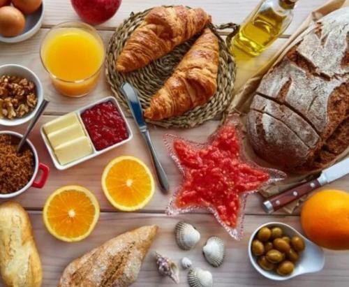 une table avec différents types de pain et autres denrées alimentaires dans l'établissement Soirée romantique LOVE ROOM, à Allez-et-Cazeneuve