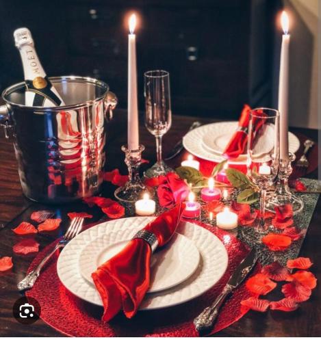 une table avec des plaques blanches, des bougies et des serviettes rouges dans l'établissement Soirée romantique LOVE ROOM, à Allez-et-Cazeneuve