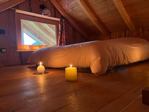 - un lit dans une chambre avec deux bougies au sol dans l'établissement Cabane Insolite de la Semine, à La Pesse