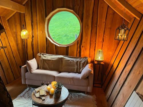 - un salon avec un canapé et une fenêtre ronde dans l'établissement Cabane Insolite de la Semine, à La Pesse