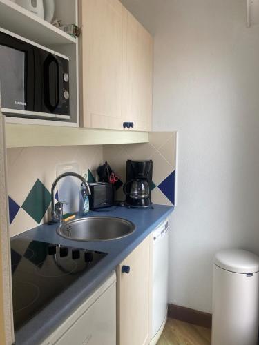 une petite cuisine avec un évier et un micro-ondes dans l'établissement La Belle Vue by Tranquil at Home, à Pornichet