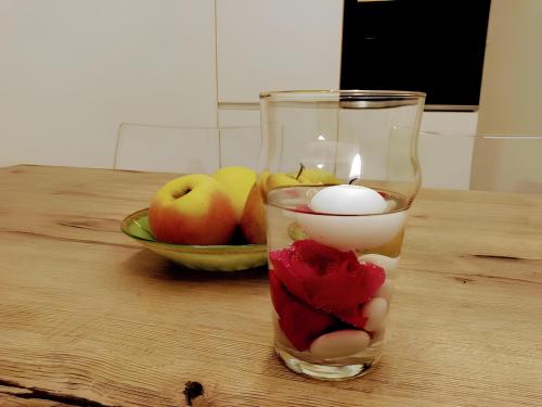 a candle on a table with apples and a bowl of fruit at Over the Castle Apartment in Trento