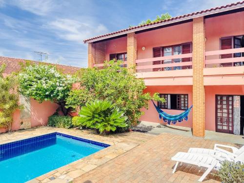 a villa with a swimming pool in front of a house at Casa espaçosa a apenas 30 minutos de SP in Sao Paulo