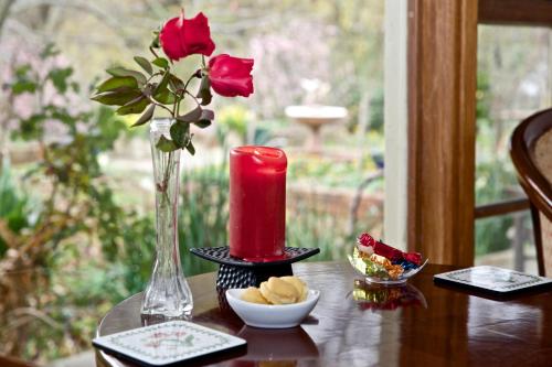 a candle and a vase with red roses on a table at Holly Lane Mews in Yarra Glen