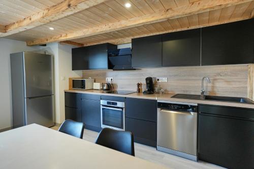 une cuisine avec des armoires noires et des appareils en acier inoxydable dans l'établissement Le Perchoir, Gîte 7 personnes, Le Grand Valtin, à Ban-sur-Meurthe-Clefcy