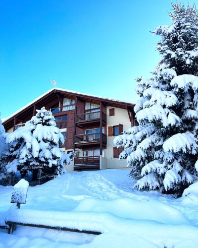 a building covered in snow with trees in front of it at Appartement Crest Voland - Aux pieds des pistes in Crest-Voland