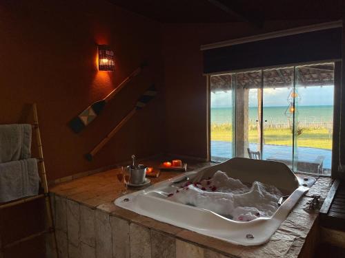 a bath tub in a bathroom with a view of the ocean at Pousada Spa dos Amores in São Miguel do Gostoso