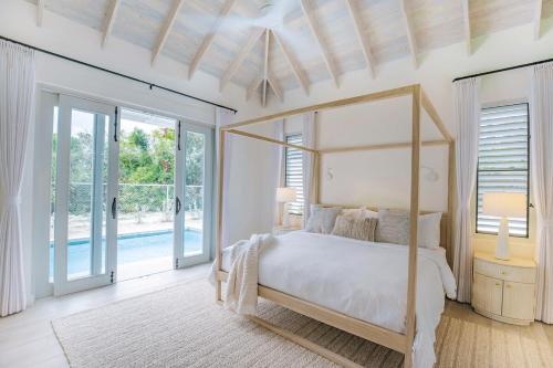 a bedroom with a canopy bed and a pool at 118 Villa Aloe in Jolly Harbour