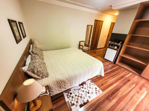a small bedroom with a bed and a wooden floor at Pousada Victoria Villa By Nacional Inn - A 800 metros da Vila Capivari in Campos do Jordão