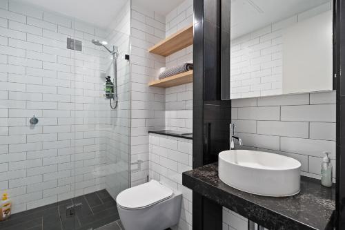 a white bathroom with a toilet and a sink at 04M New 1BR apartment near Airport and City with Free visitor parking in Sydney