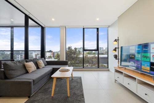 a living room with a couch and a flat screen tv at 04M New 1BR apartment near Airport and City with Free visitor parking in Sydney