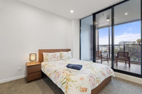 a bedroom with a bed and a large window at 04M New 1BR apartment near Airport and City with Free visitor parking in Sydney