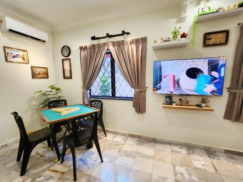 a dining room with a table and a tv at Ipoh 168 Taman Pelangi, Persiaran Halaman Ampang Ipoh in Ipoh